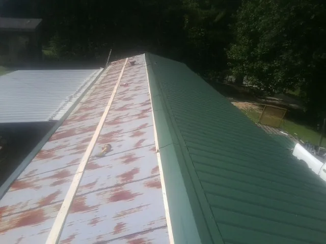 Old rusted panels beside newly installed green metal roofing — Wind Damage Roof Repair by Roofing Brothers in Roanoke