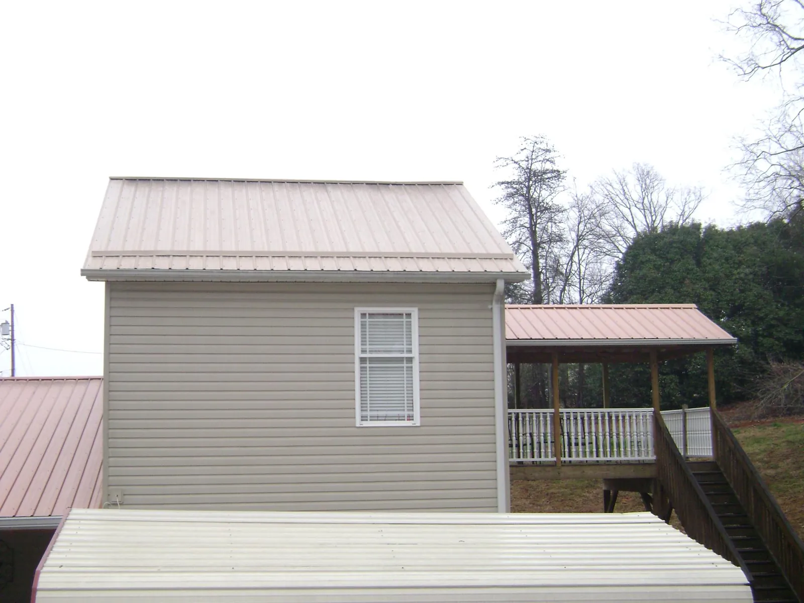 Tan metal roofs on a two story addition and attached porch, from a Roof Replacement job in Roanoke